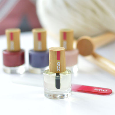 Webseitenbild: Nail and cuticle care oil. Im Hintergrund: Glass Nagelfeile und drei Nagellacke in verschiedenen Farben. 